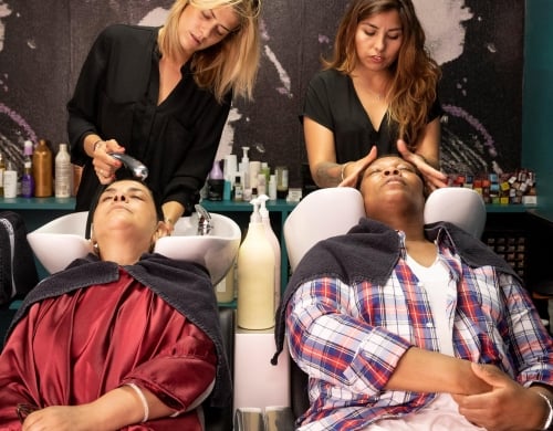 Deux coiffeurs font un shampoing pour deux clients.