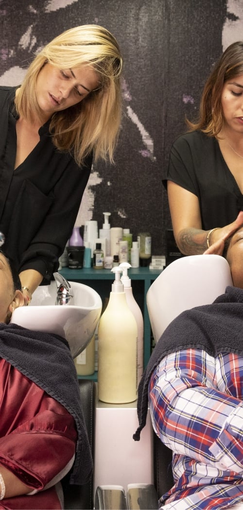 Two hairdressers making a shampoo for clients.